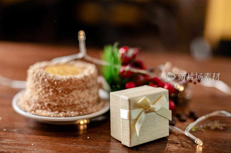 圣诞咖啡，木桌上有花环和灯。与新年礼品盒合影。甜点，蛋糕和丝带礼物。庆祝的心情。圣诞快乐，万事如意