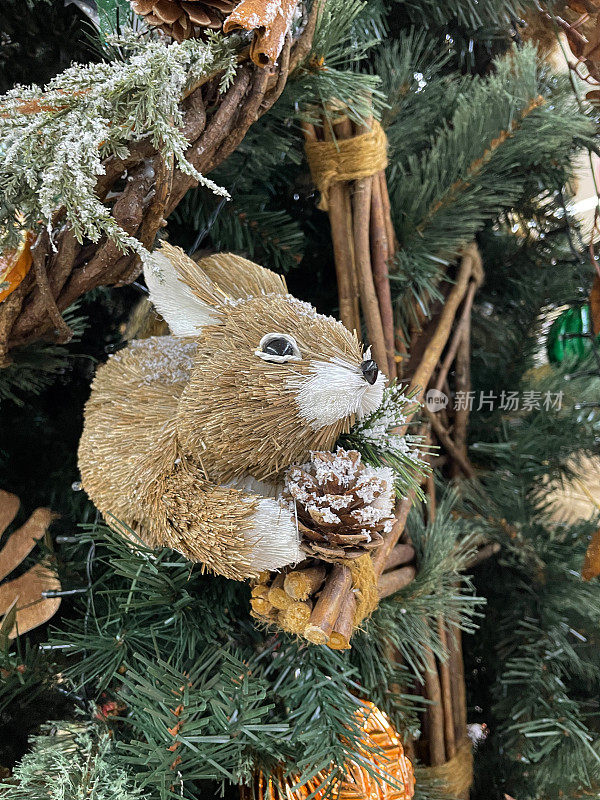 形象的兔子装饰物悬挂在人造圣诞树的树枝上，树枝上的星星和云杉针上覆盖着人工喷雪，背景上模糊的白色神仙灯