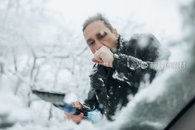 冬季开车。冬天的一天，这个人正在擦车窗上的雪。冬季，一名白人男子正在用刷子把车里的雪清除掉。