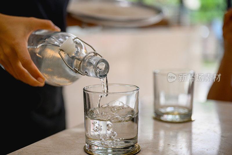 将水从玻璃瓶中倒入玻璃杯