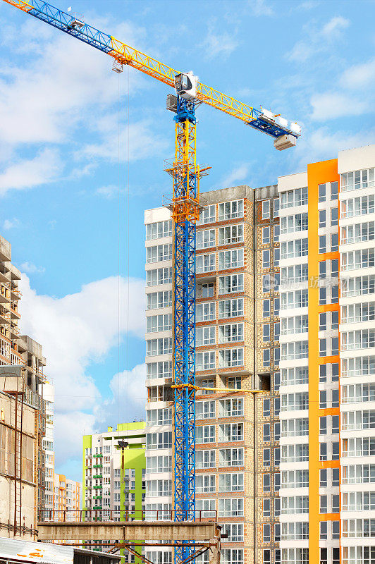 一座塔式起重机巍然耸立在一座现代高层住宅建筑工地上。