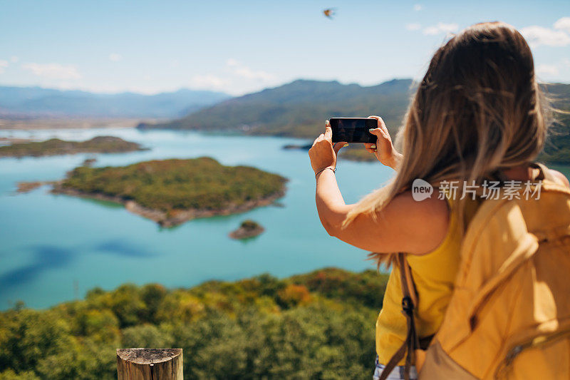 一个难以辨认的女子徒步旅行者拍摄美丽的冰川湖，燕子飞过