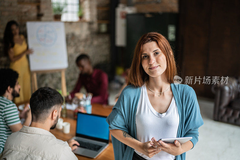 一名年轻的女商人在办公室里手持数码平板电脑的肖像