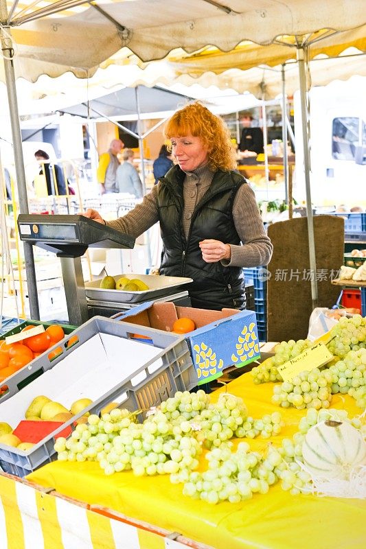 在她的市场摊位上的女蔬菜水果商