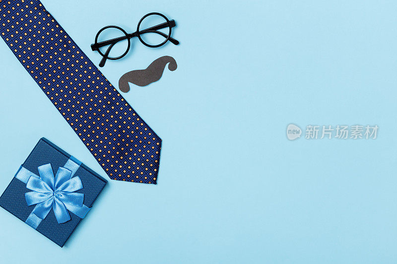父亲节概念爸爸庆祝。蓝色背景的领带、眼镜和礼物盒。