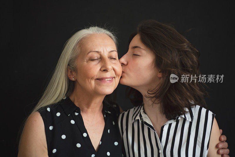 老祖母和她的孙女在黑色的土地上亲吻她的肖像