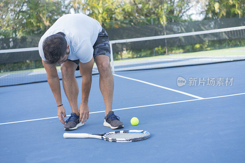 男选手在网球场系鞋带