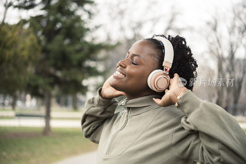 一个快乐的非洲女孩在公园里享受音乐和锻炼的肖像