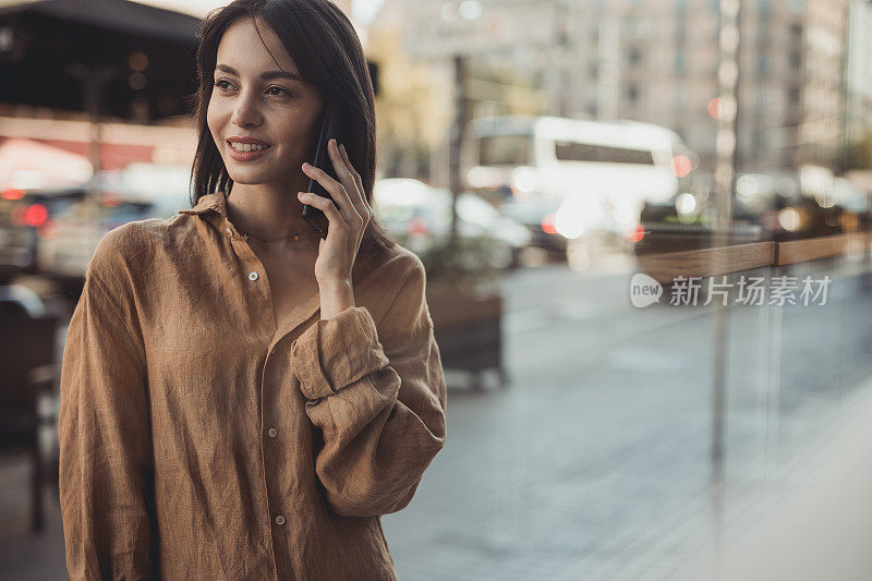 一个小女孩，走在西班牙首都的街道上，用着手机