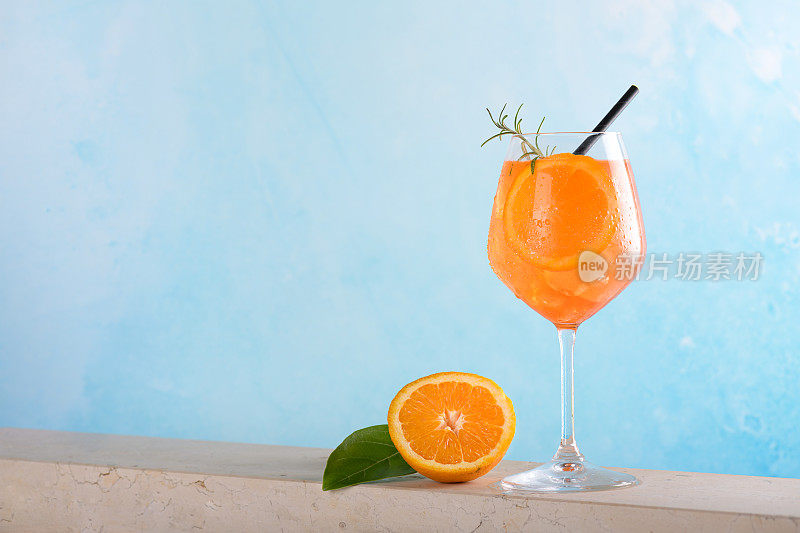 经典的意大利开胃酒鸡尾酒，在浅蓝色的背景上加入冰块和一片橙子