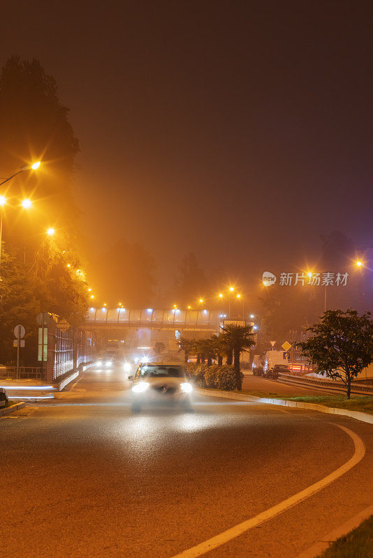 夜晚发光朦胧的路。汽车在雾蒙蒙的夜晚行驶在路上。模糊图像