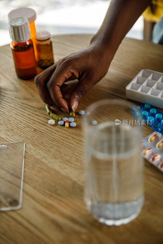 年轻女子拿起一颗药丸从咖啡桌上，当安排她的药物在药片整理箱