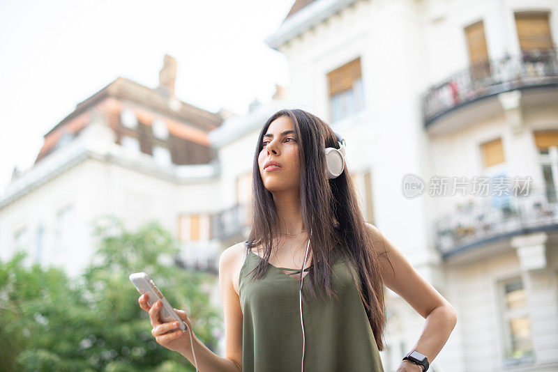 一个美丽的年轻女子享受户外和听音乐的肖像