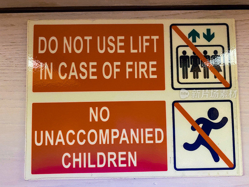 电梯门上的红色和白色矩形警示标志特写图像，“火灾时请勿使用电梯”，“无陪伴儿童勿入”，安全协议