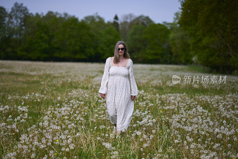 草地上，女人走在褪了花的蒲公英丛中
