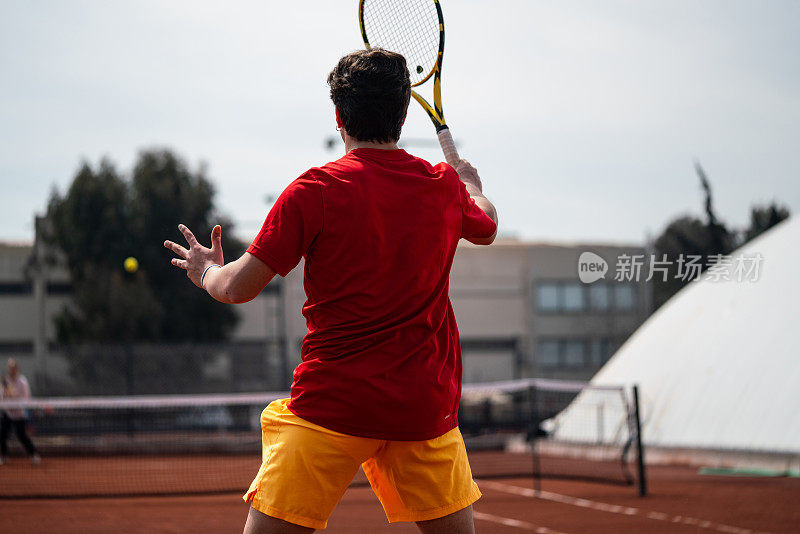 男子网球运动员在红土场上正手击球，重点放在前景垂直网球上