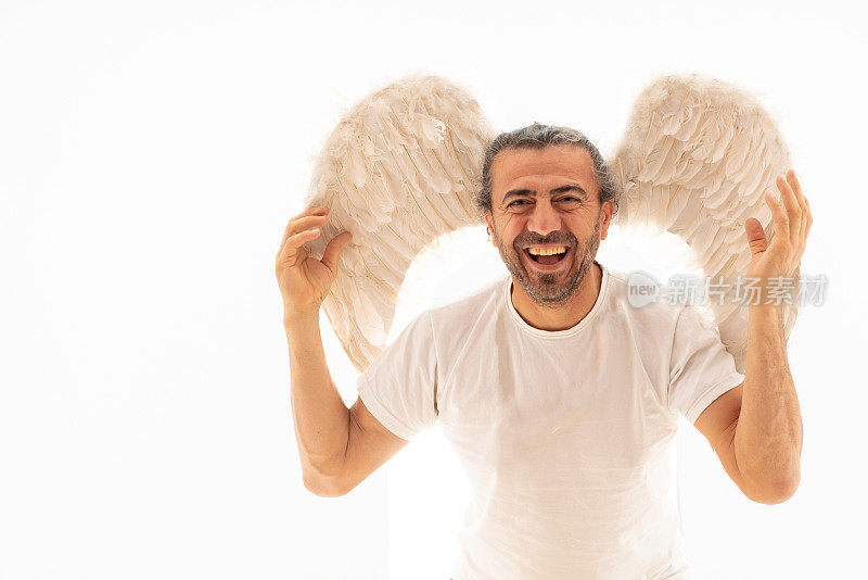 一个穿着天使翅膀的幽默男人站在白色背景上的肖像