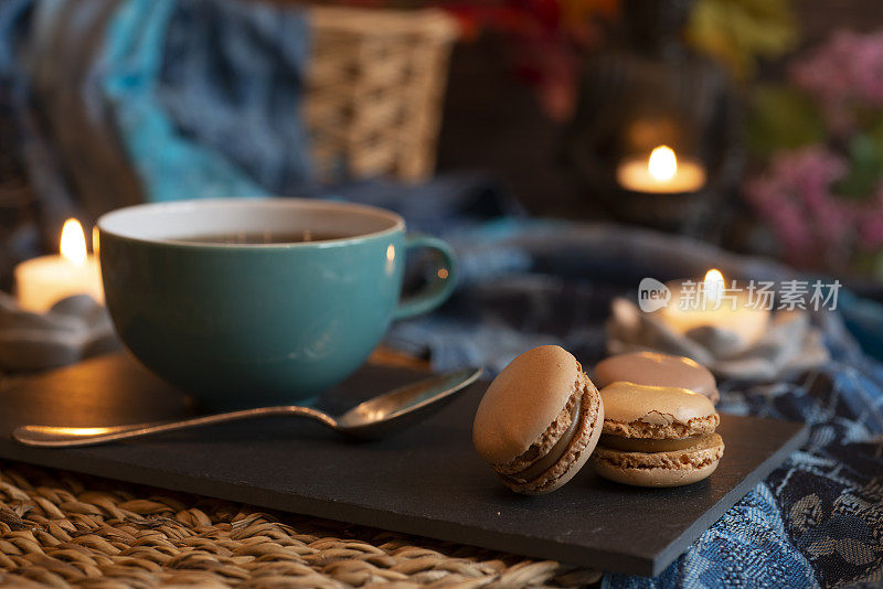 茶或咖啡在杯子里，马卡龙与佛和烛光-休息