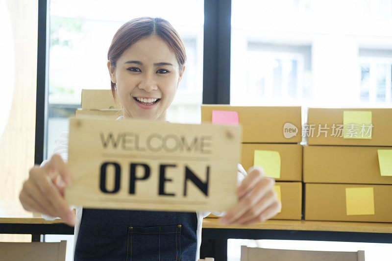 女网上企业主举着欢迎、开放的牌子。