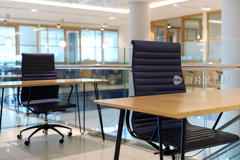 开放式共享办公室外观现代，布局宽敞，一排排空桌子和办公椅摆放整齐。