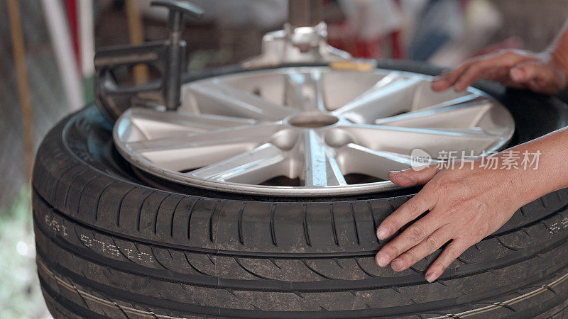 机械师有修理汽车的专业知识和技能，工作是在车库里给合金车轮装新轮胎。汽车维修及服务。工人用专用机器在轮辋上安装轮胎。轮胎更换概念。