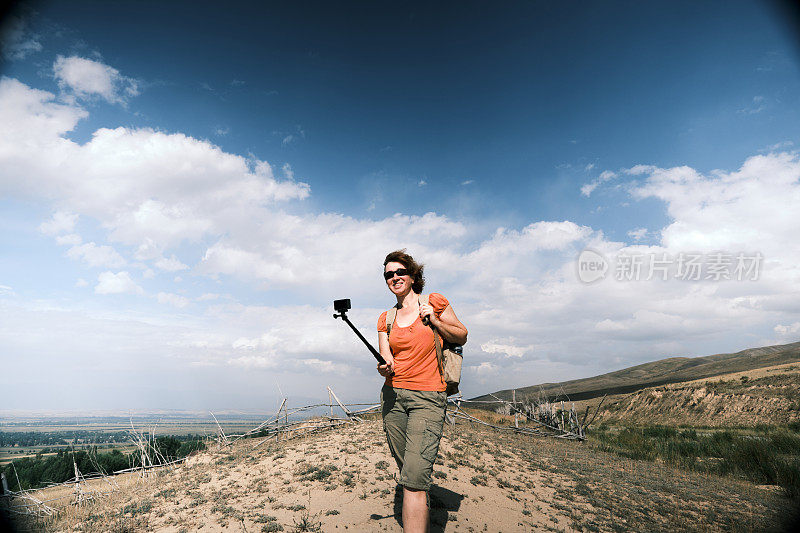 快乐的女游客在山麓徒步旅行，她的徒步旅行流