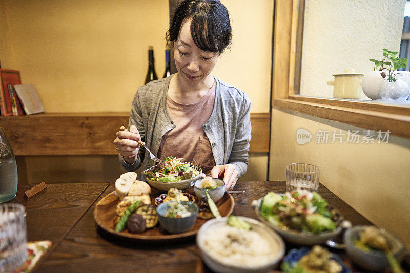 一位亚洲妇女在素食餐厅吃素食午餐。