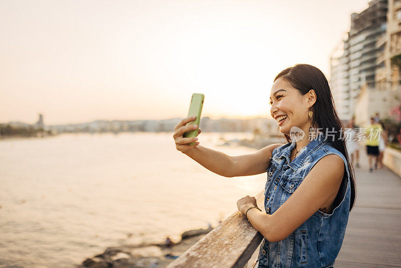 一位面带微笑的女士用手机自拍，欣赏周围的自然风光