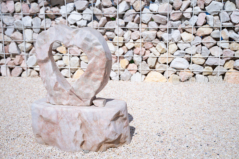 在许多小石头的地板上放置了一个雕刻成心形的石基座