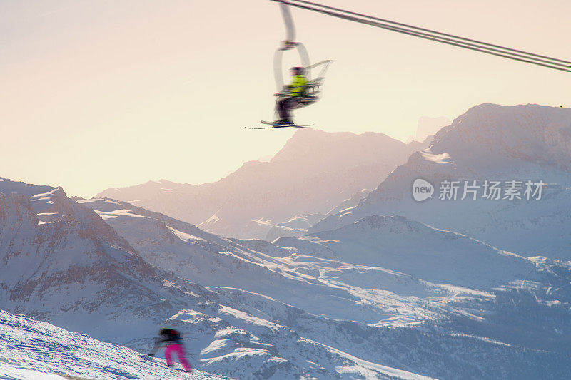一个滑雪者在另一个滑雪者上方的缆车上
