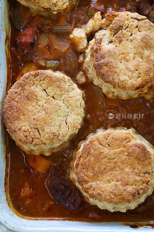 全画幅的自制牛肉和啤酒砂锅菜在砂锅菜，与金色的cobblers(美国饼干)漂浮在表面，高架视图