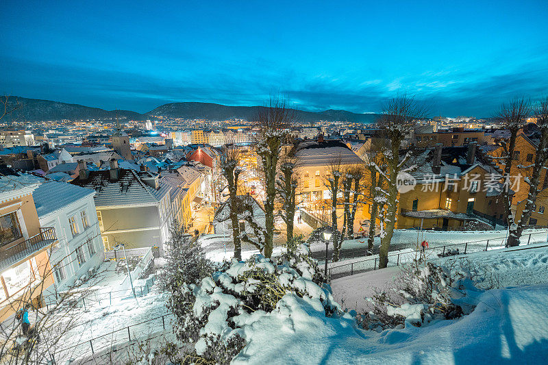 美丽的夜晚全景卑尔根，从房屋之间俯瞰。从房子中间往下看，就是缆车站。屋顶上的雪，美丽的景色。