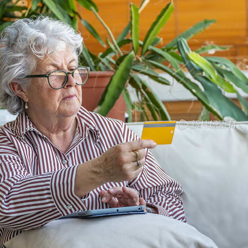 一位老妇人正在查看银行信用卡，以备电子商务之用
