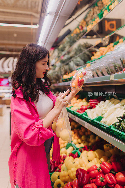 年轻的韩国妇女在杂货店购物时不带塑料袋。素食零浪费女孩在超市挑选新鲜水果和蔬菜。系列的一部分