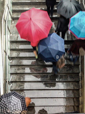 地铁楼梯上撑着雨伞的人们的鸟瞰图