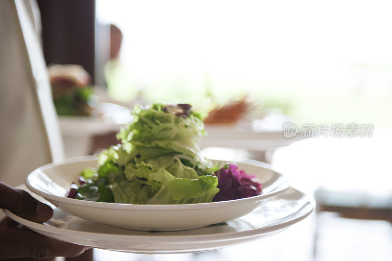 在餐馆里，服务员用盘子把食物端到桌子上