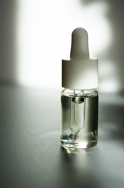 化妆或医疗用的带吸管的玻璃瓶。皮肤护理的概念。自然光硬，阴影深。——图片