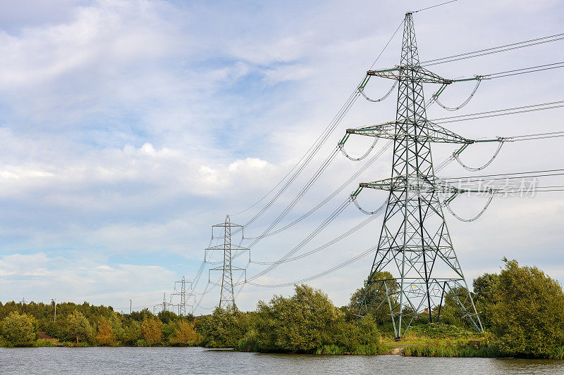 在切斯特菲尔德附近的德比郡，一个绿树成荫的钓鱼湖，有一个电线塔和电线通向远方。