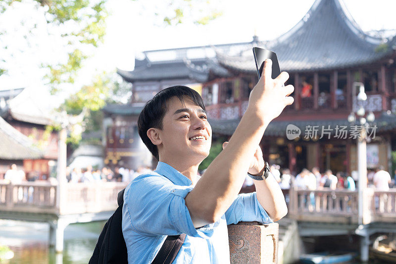 年轻的亚洲男子与手机自拍