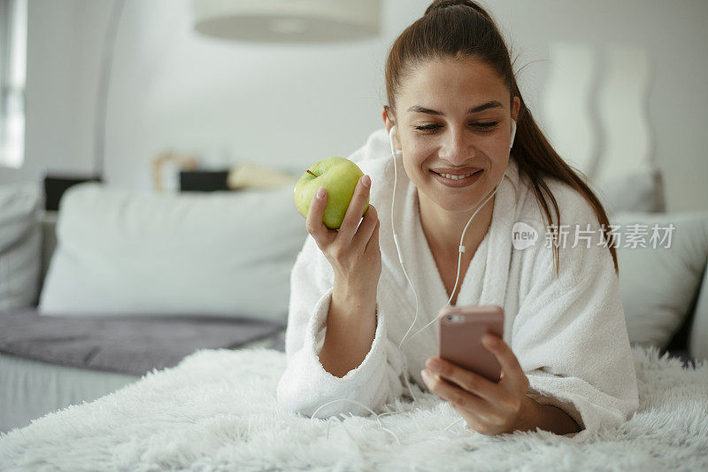 年轻漂亮的女人发短信上网在家里的沙发上。库存图片