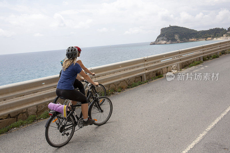 妈妈和女儿在空旷的沿海公路上骑自行车