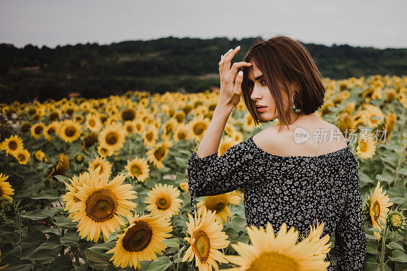 年轻女孩欣赏着美丽的向日葵田