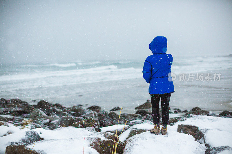 俯瞰挪威罗浮敦白雪覆盖的海滩的女人。