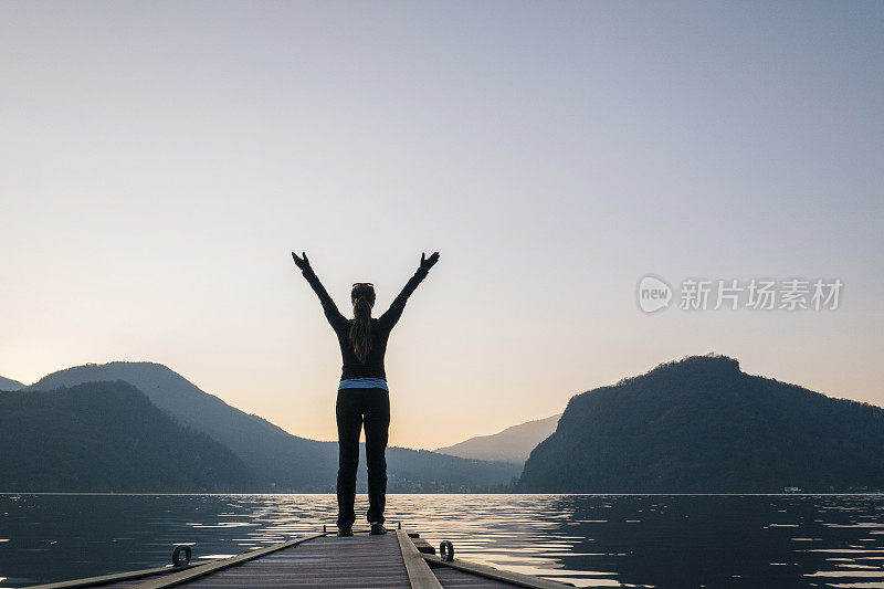 在码头的尽头，一名女子在湖上迎接日出