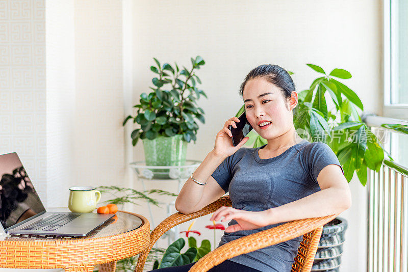 在客厅里使用智能手机的亚洲年轻女子