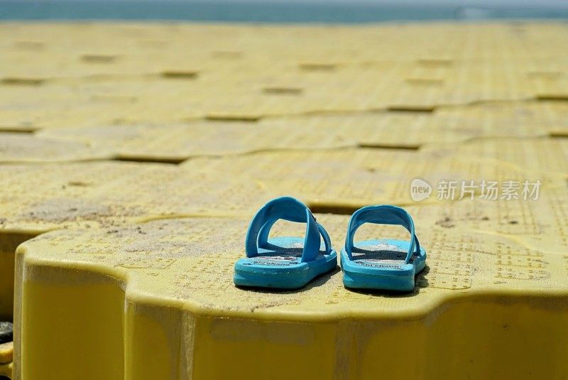 脚上的拖鞋在凉鞋鞋和蓝色海浪水分布在沙滩白色，海背景。水的颜色又美又亮。旅游自然度假夏季概念。