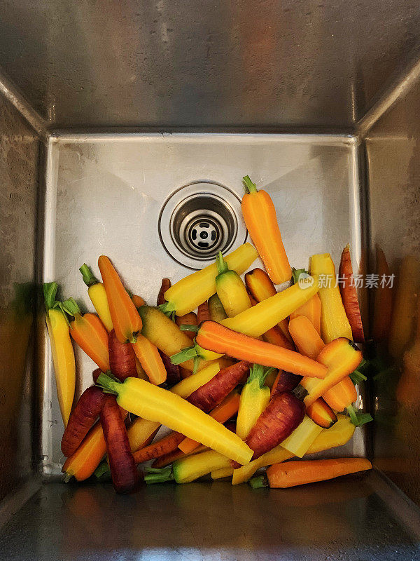 自家种植的新鲜的彩虹胡萝卜被切碎并在不锈钢水槽中清洗