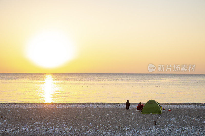 早上，朋友们坐在营地外面的海滩上