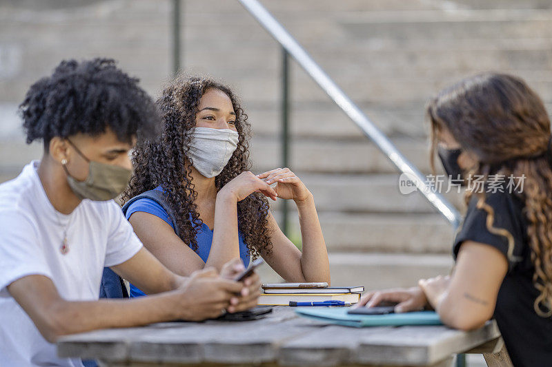 坐在校园里的学生戴着防护口罩