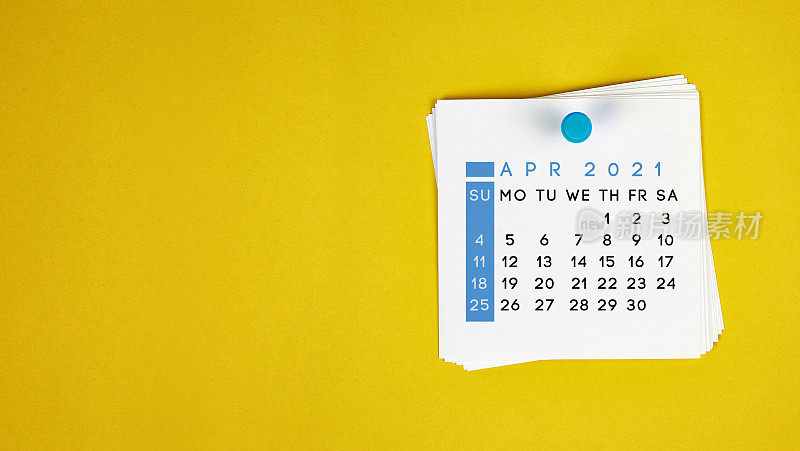 2021年4月的日历钉在黄色的背景上。